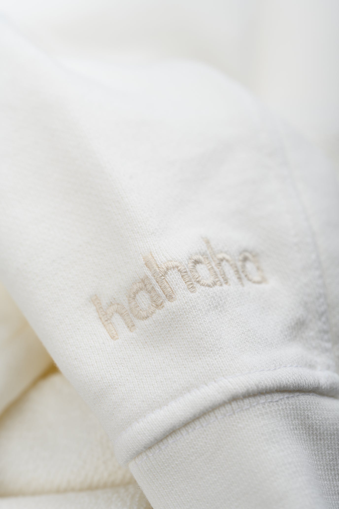 Close-up Hahaha embroidery on organic cotton kids hoodie cuff, handmade in Los Angeles