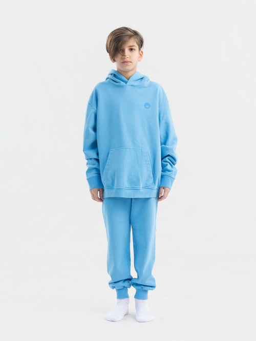 Child wearing blue Hahaha organic cotton hoodie with joggers, front view, made in Los Angeles