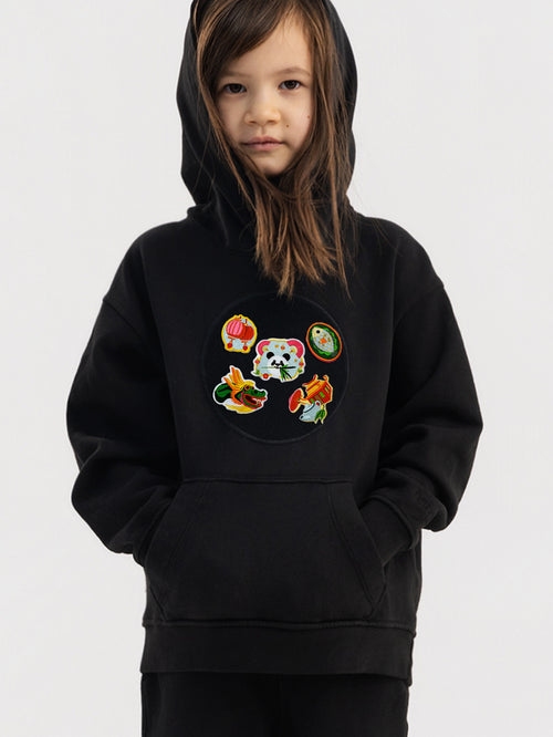 Child wearing black Hahaha hoodie with collectible patches on swappable circular patch zone