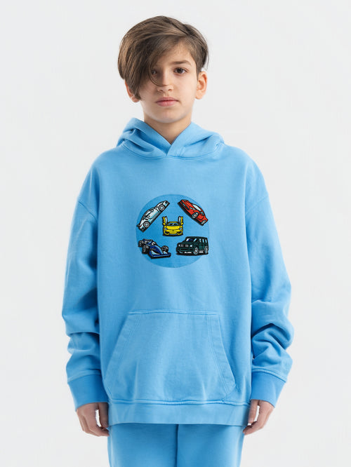 Child wearing blue Hahaha hoodie with collectible patches on swappable circular patch zone