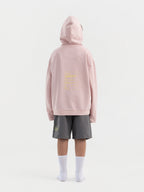 Back of dirty pink Hahaha kids hoodie with CAUTION CONTAINS HIGH LEVELS OF SNUGGLES AND GIGGLES label