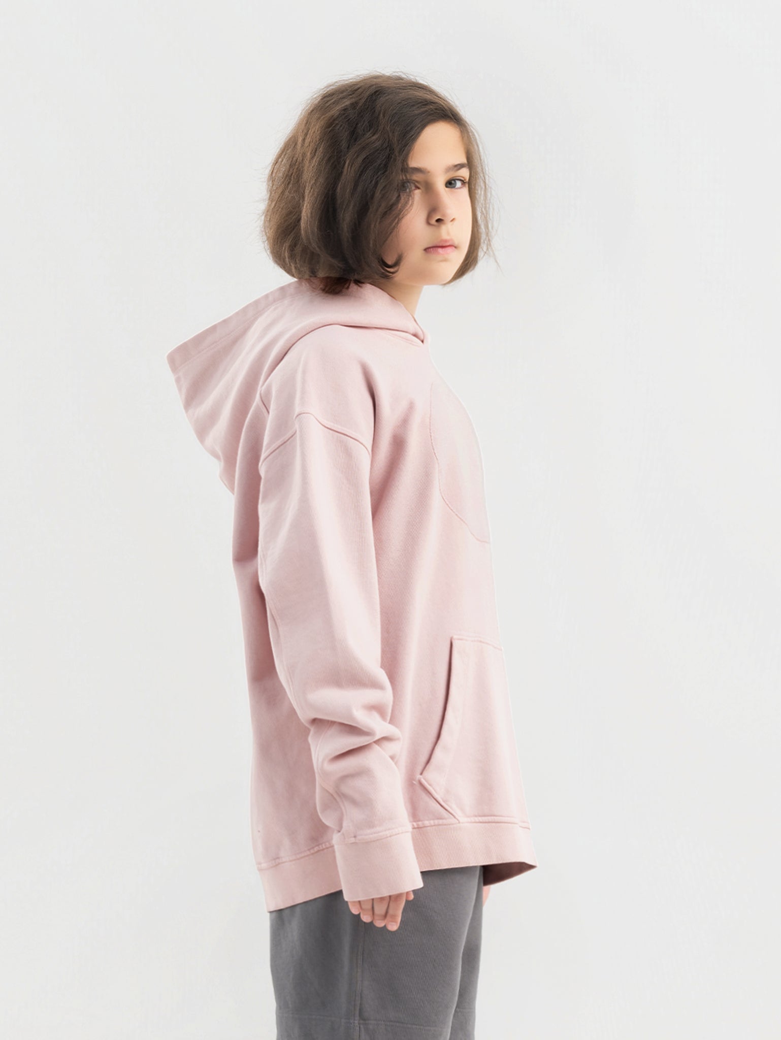 Child wearing dirty pink Hahaha hoodie with collectible patches on swappable circular patch zone