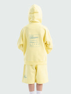 Back of light yellow Hahaha kids hoodie with CAUTION CONTAINS HIGH LEVELS OF SNUGGLES AND GIGGLES label