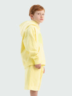 Light Yellow Hahaha organic cotton kids hoodie side profile, child looking over shoulder
