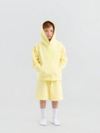 Child wearing light yellow Hahaha organic cotton hoodie with joggers, front view, made in Los Angeles