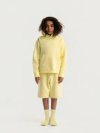 Child wearing light yellow Hahaha organic cotton hoodie with joggers, front view, made in Los Angeles