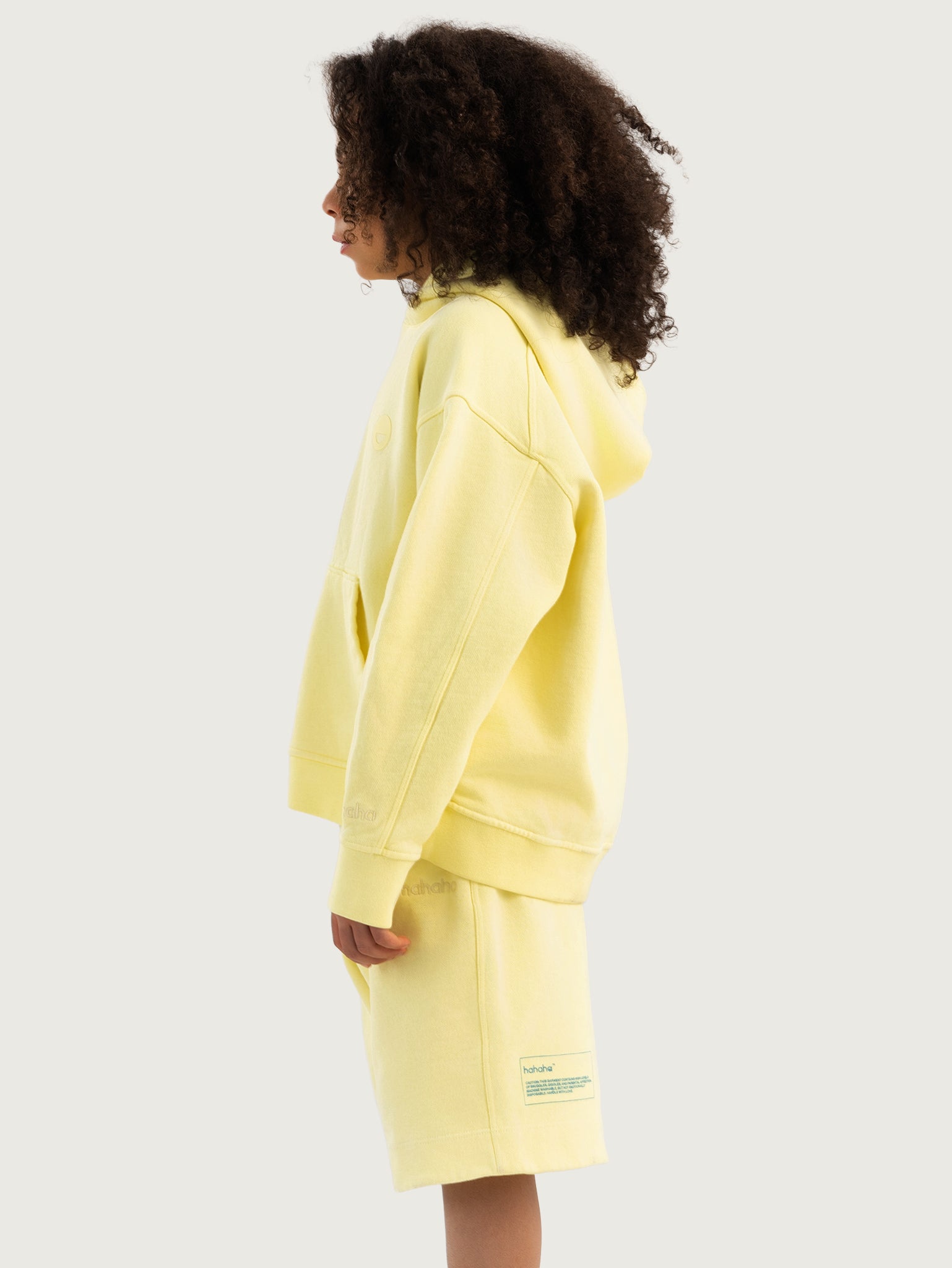 Light Yellow Hahaha organic cotton kids hoodie side view with hood up, made in California