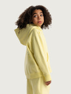 Light Yellow Hahaha organic cotton kids hoodie side profile, child looking over shoulder