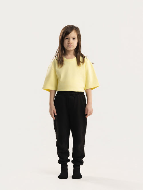 Child wearing black Hahaha organic cotton kids jogger pants, front view, made in Los Angeles