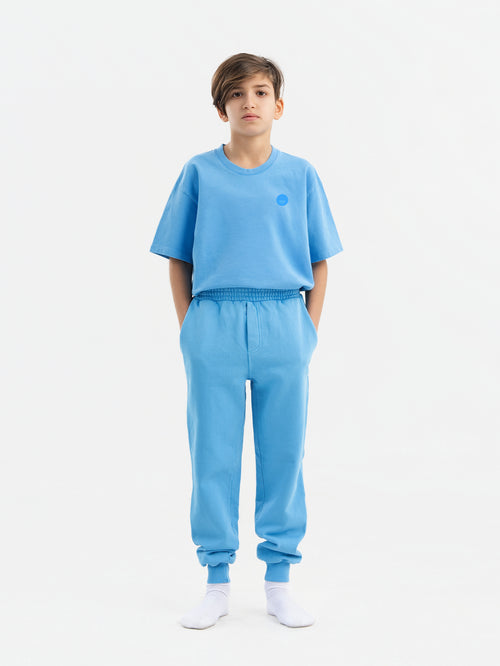 Child wearing blue Hahaha organic cotton kids jogger pants, front view, made in Los Angeles