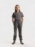 Child wearing stone grey Hahaha organic cotton kids jogger pants, front view, made in Los Angeles