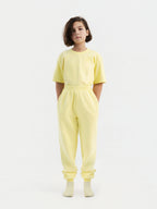 Child wearing light yellow Hahaha organic cotton kids jogger pants, front view, made in Los Angeles