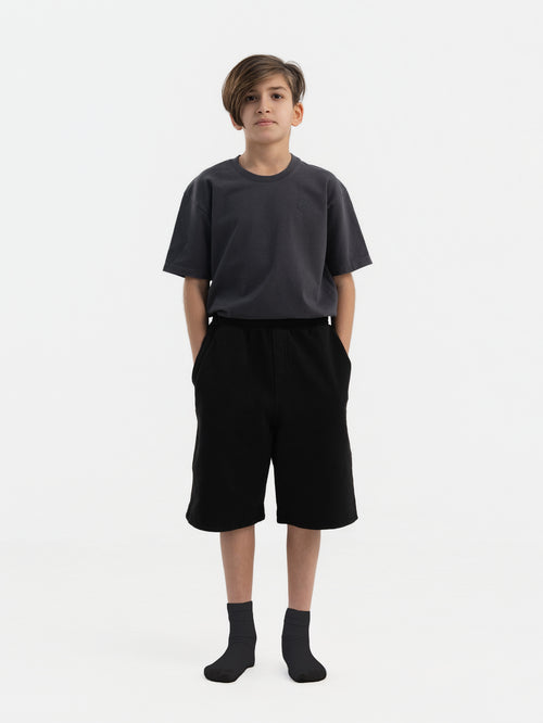 Child wearing black Hahaha organic cotton kids shorts, front view, made in Los Angeles