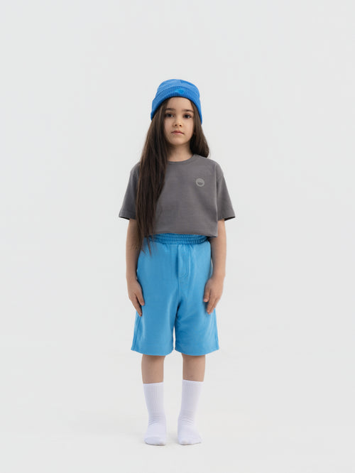 Child wearing blue Hahaha organic cotton kids shorts, front view, made in Los Angeles