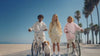 Kids in Hahaha organic cotton hoodies with patches, standing with bikes and a beagle on the beach